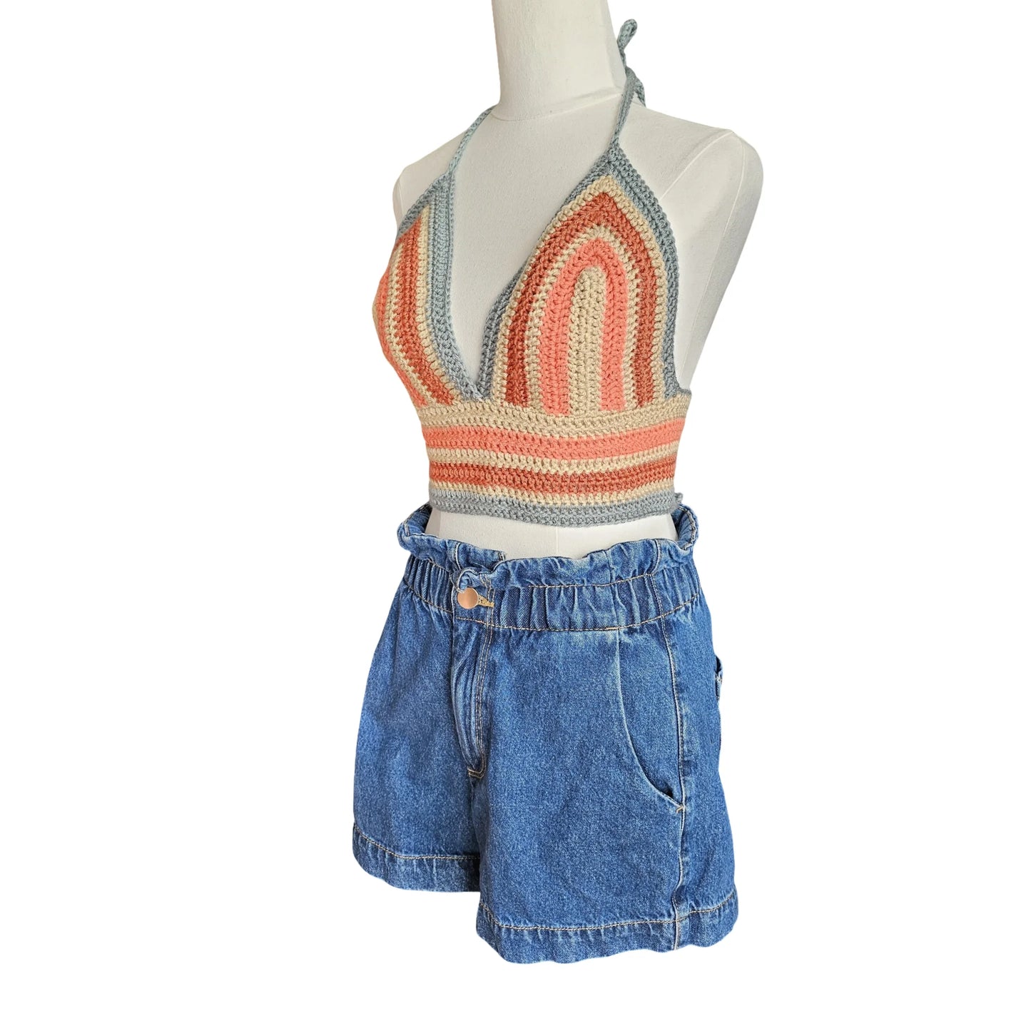 Mannequin wearing a colorful knit top and blue denim shorts on a white background