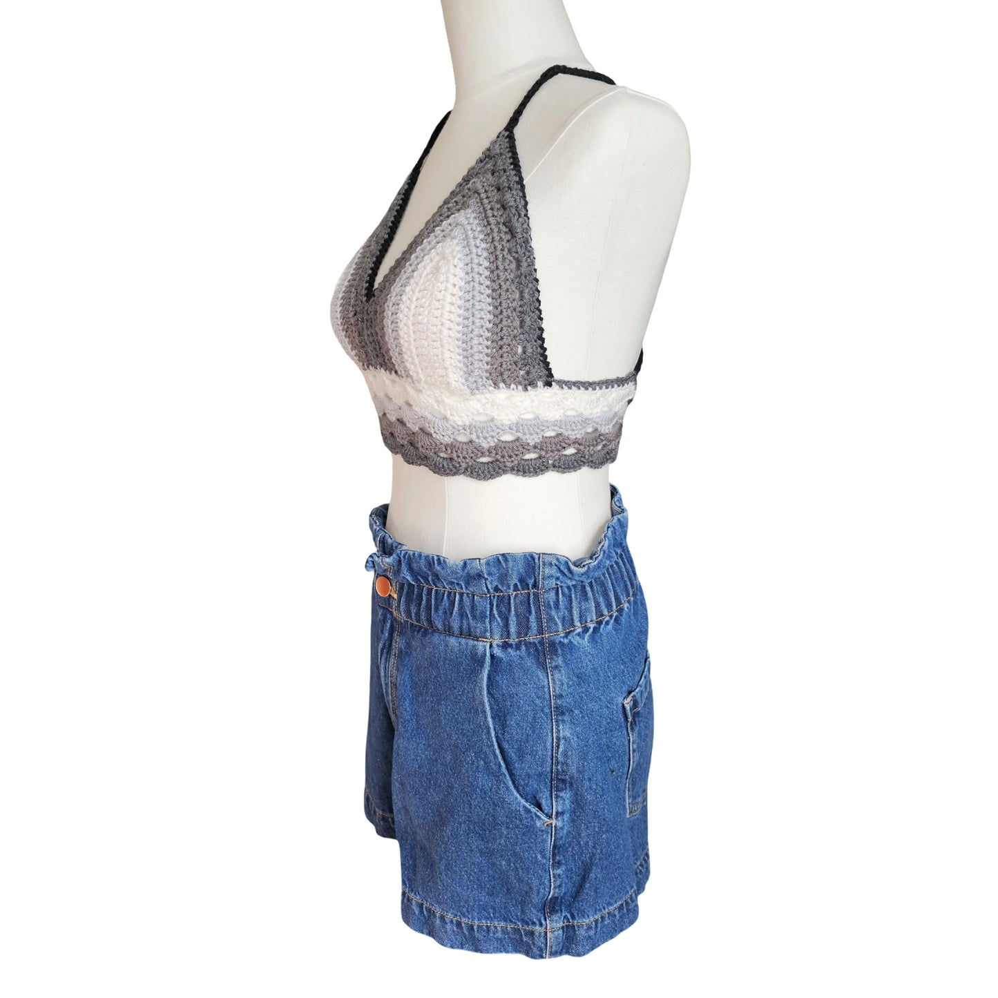 Mannequin wearing a crochet patterned top and blue shorts on a white background