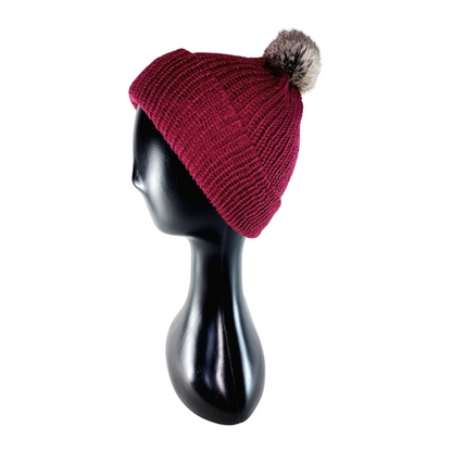 Red knit beanie with a gray pom-pom on a black mannequin head against a white background
