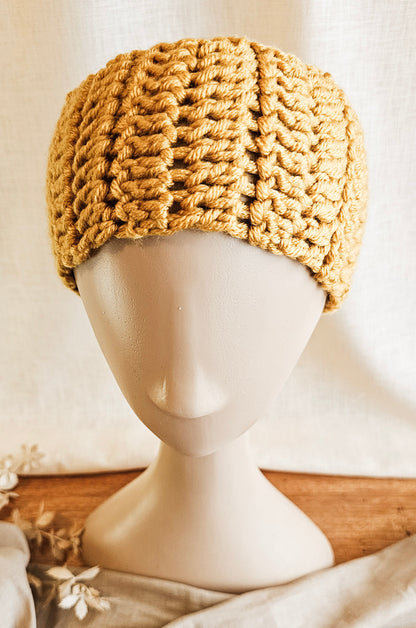 Knitted beige headband on a mannequin head against a neutral background