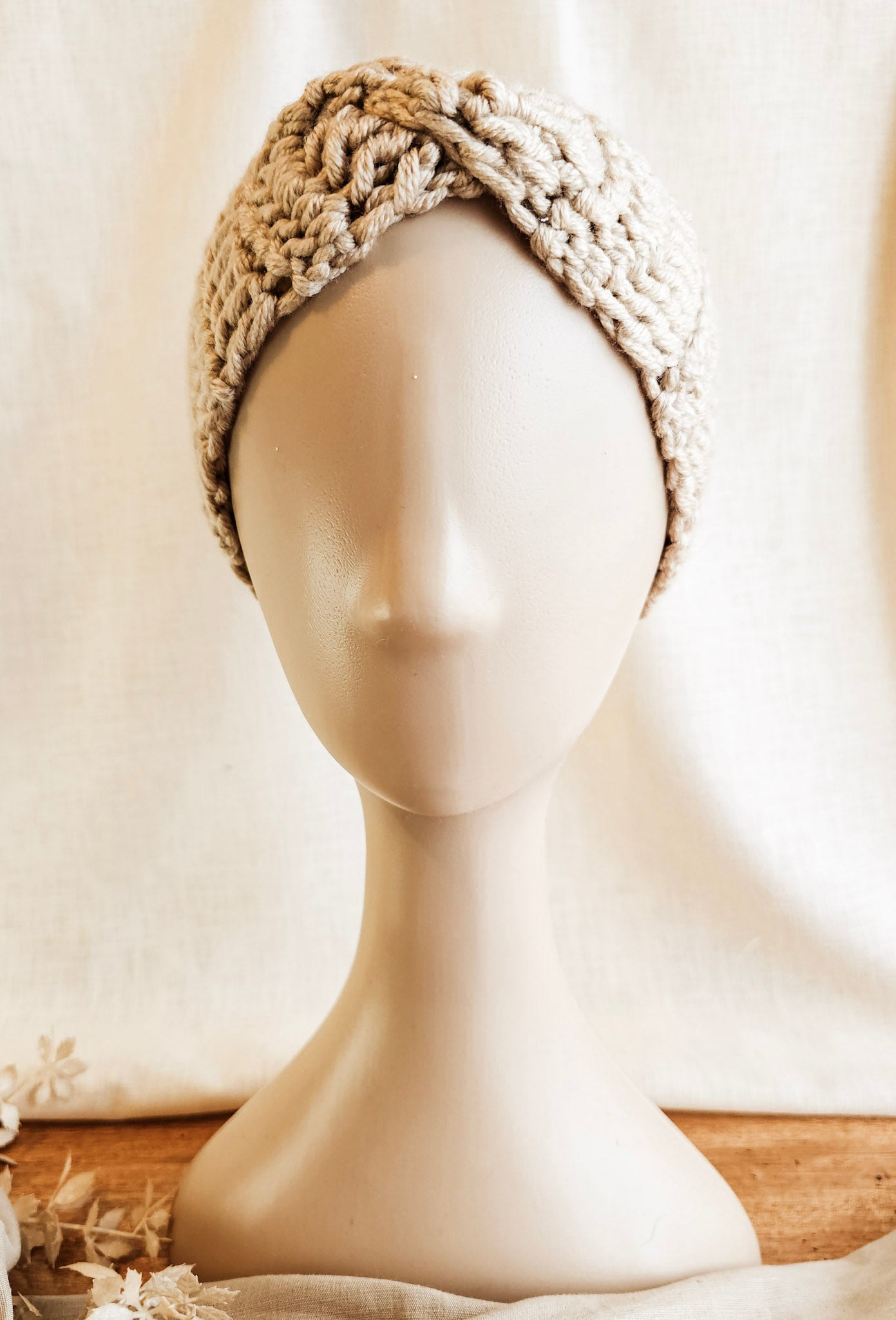 Knitted headband on a mannequin head against a neutral background