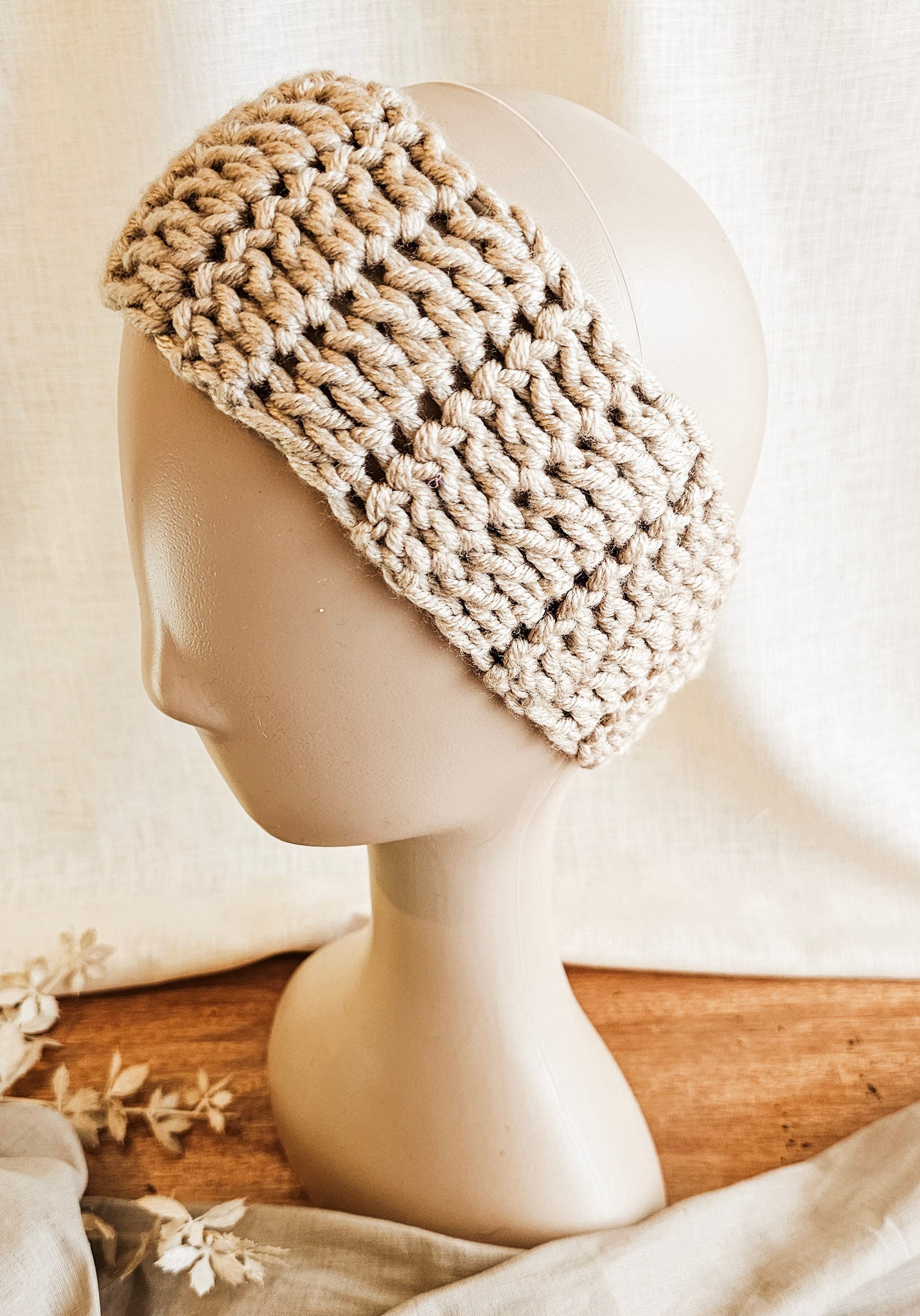 Beige knitted headband on a mannequin head with a soft background