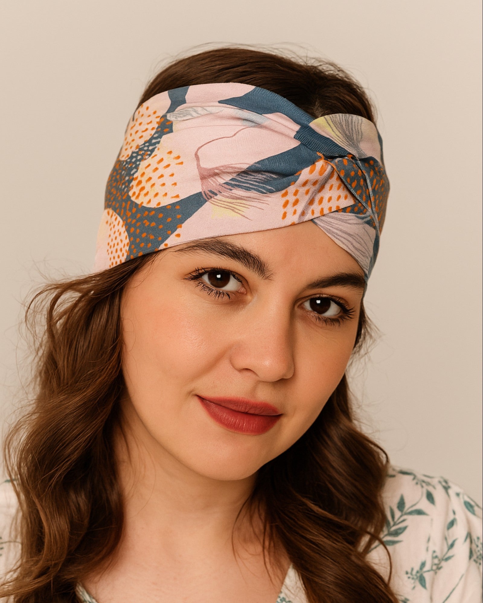 Woman wearing a colorful patterned Knotted headband against a neutral background