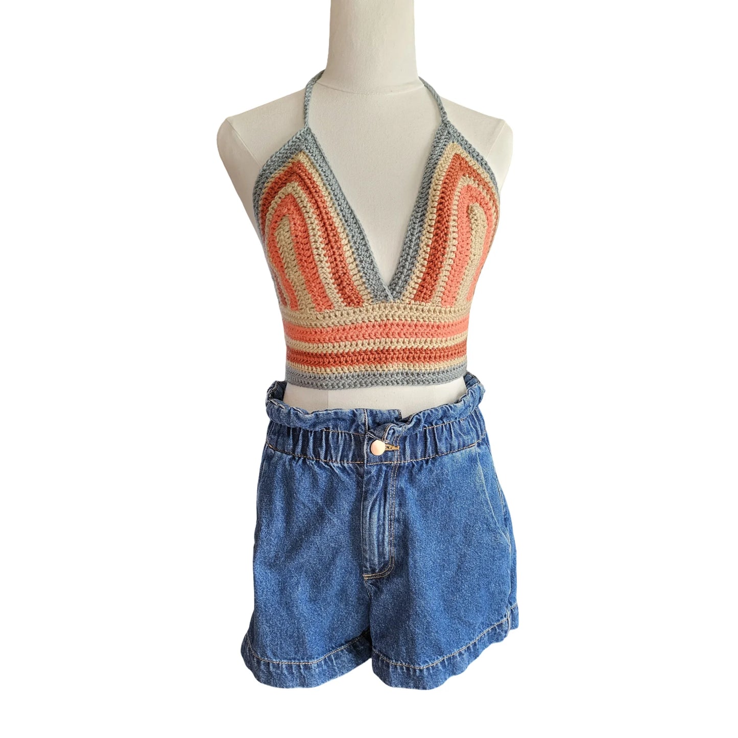 Mannequin wearing a colorful knit top and blue denim shorts on a white background
