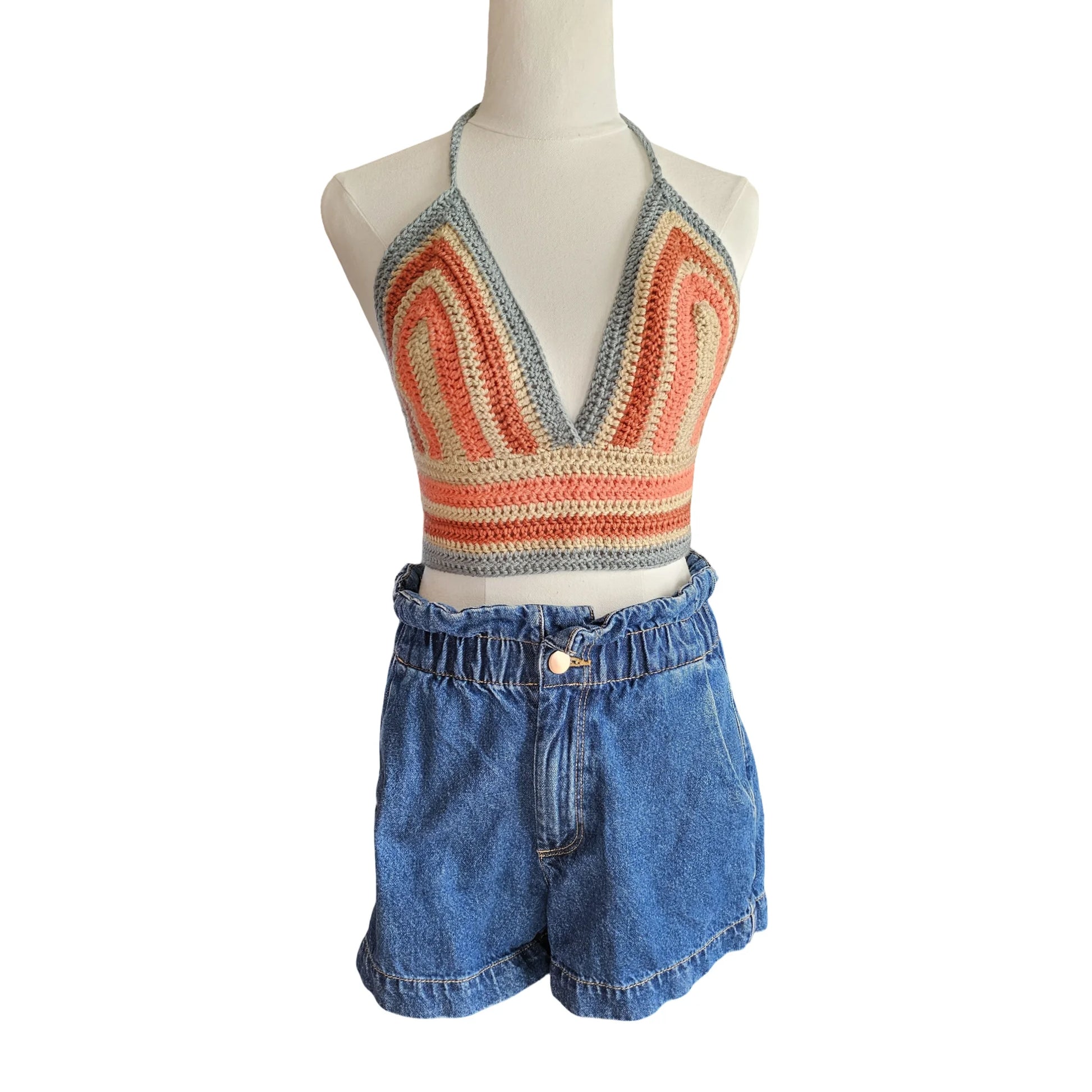 Mannequin wearing a colorful knit top and blue denim shorts on a white background