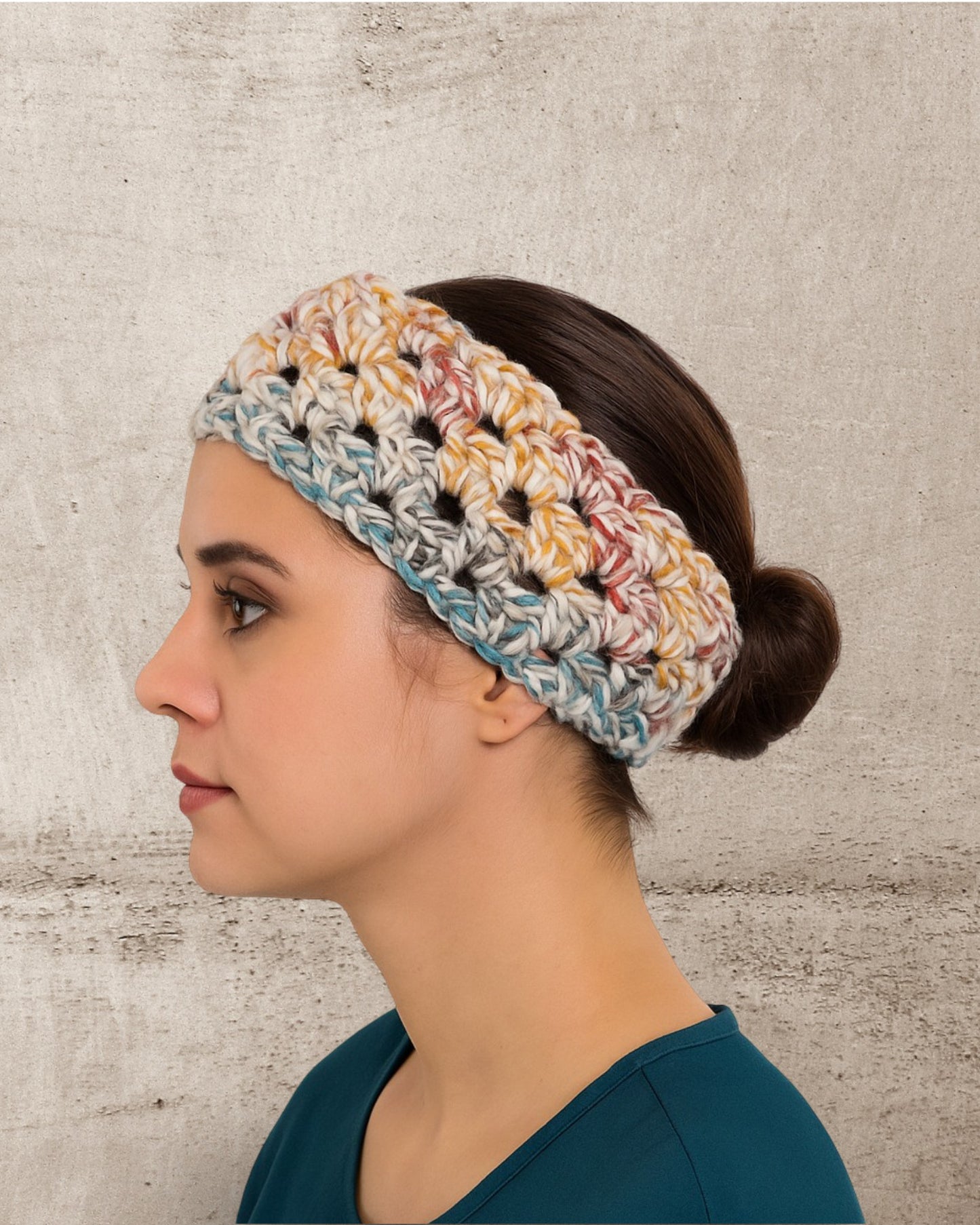 Woman wearing a colorful Crochet headband against a textured wall.