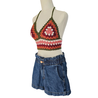 Colorful crochet top and denim shorts on a mannequin against a white background