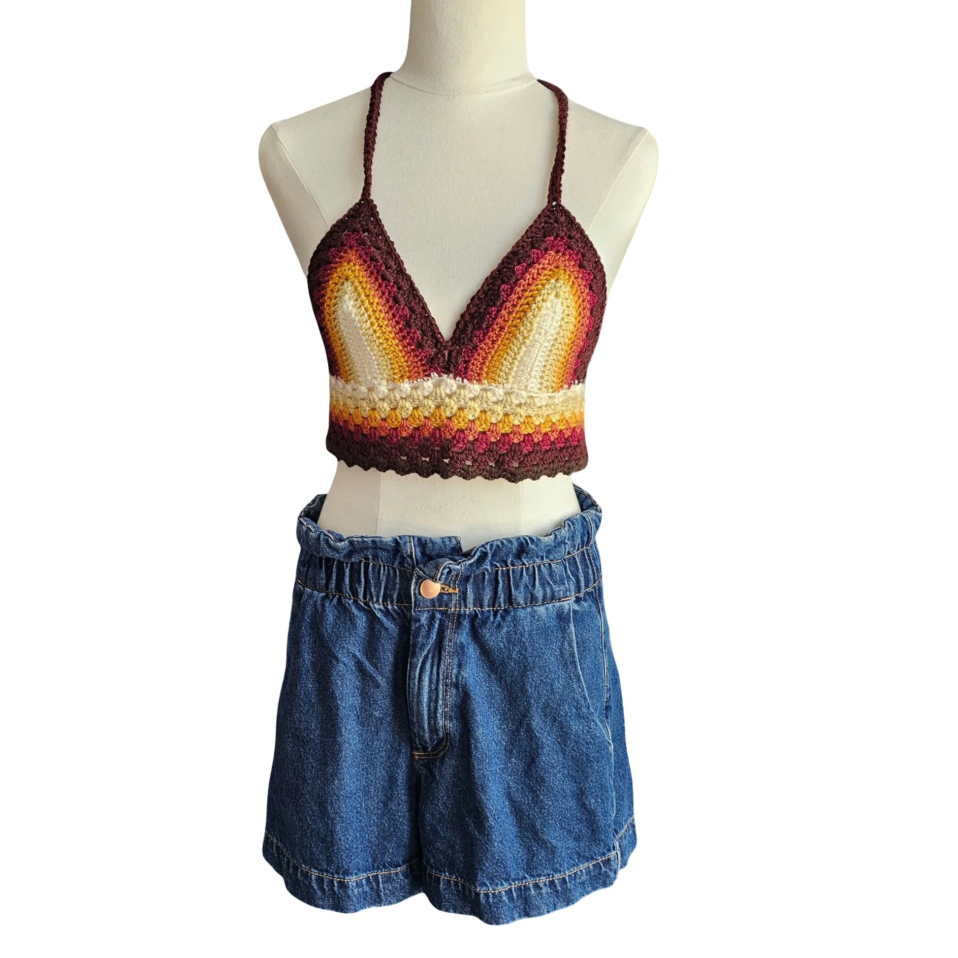 Mannequin wearing a colorful crochet top and blue denim shorts on a white background
