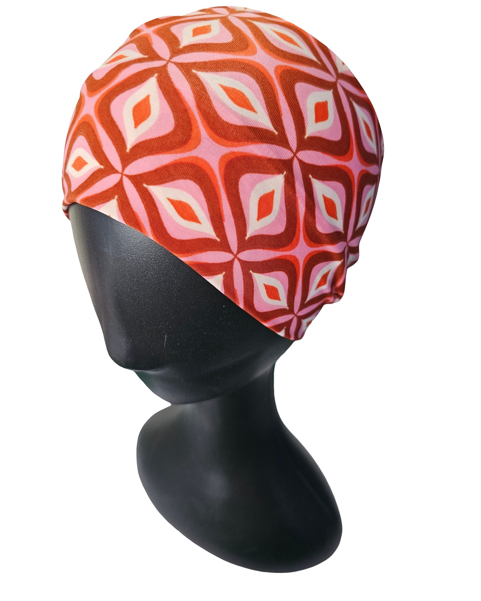 Red and pink patterned headscarf on a black mannequin head against a white background