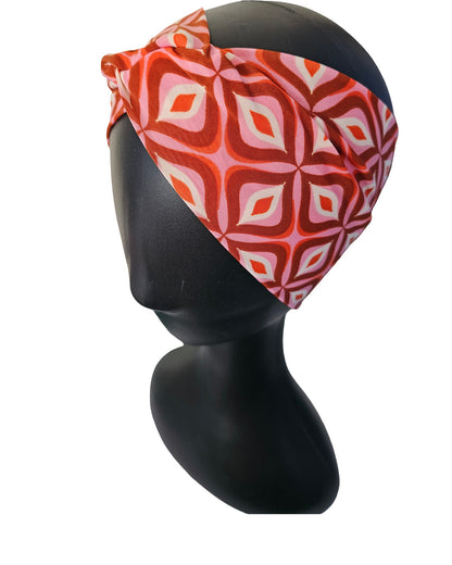 Red and white patterned headscarf on a black mannequin head against a white background