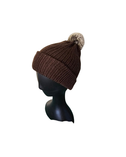 Brown knit beanie with a pom-pom on a black mannequin head against a white background