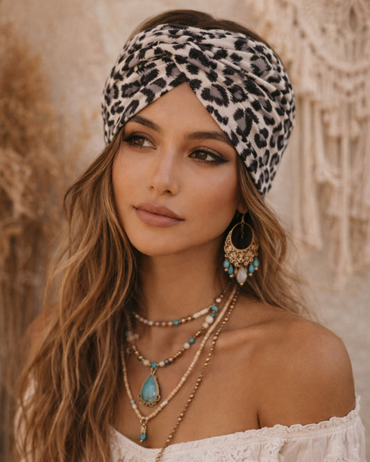 Woman wearing a leopard print headband and layered necklaces against a neutral background
