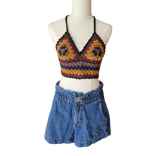 Colorful crochet top and denim shorts on a mannequin against a white background