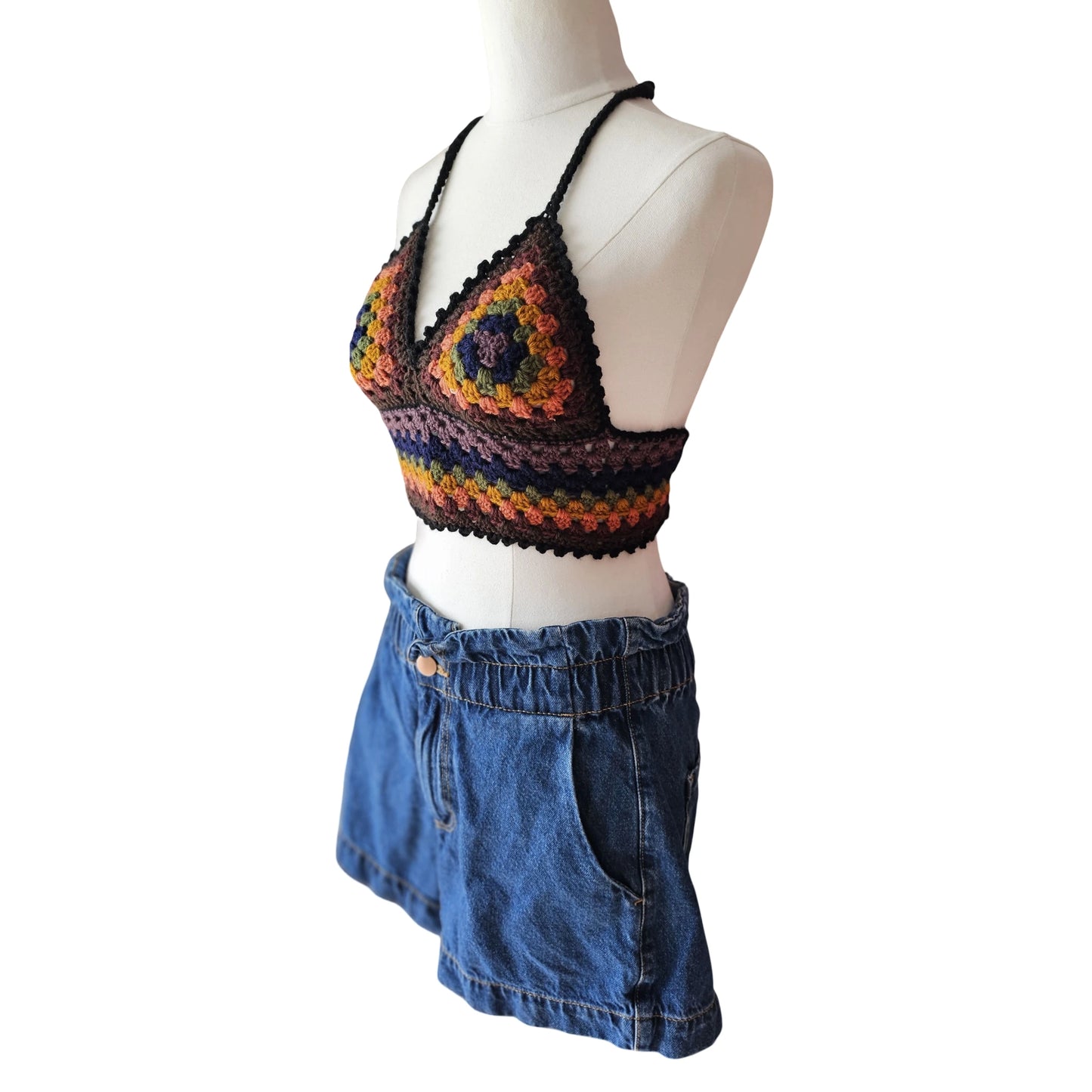 Mannequin wearing a colorful crochet top and blue denim shorts on a white background