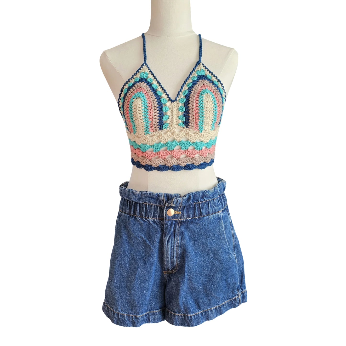 Colorful crochet top and denim shorts on a mannequin against a white background