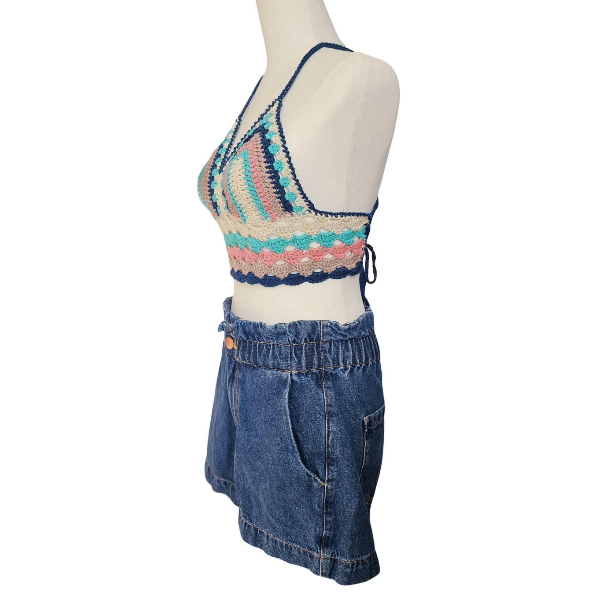 Mannequin wearing a colorful crochet top and blue denim shorts on a white background