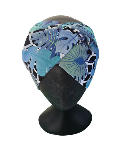 Colorful headscarf with a tropical leaf pattern on a mannequin head against a white background