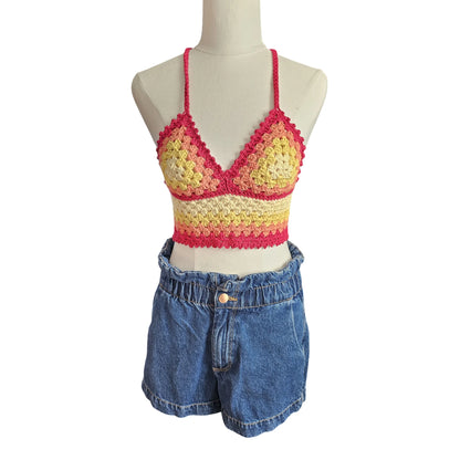 Colorful crochet top and denim shorts on a mannequin against a white background