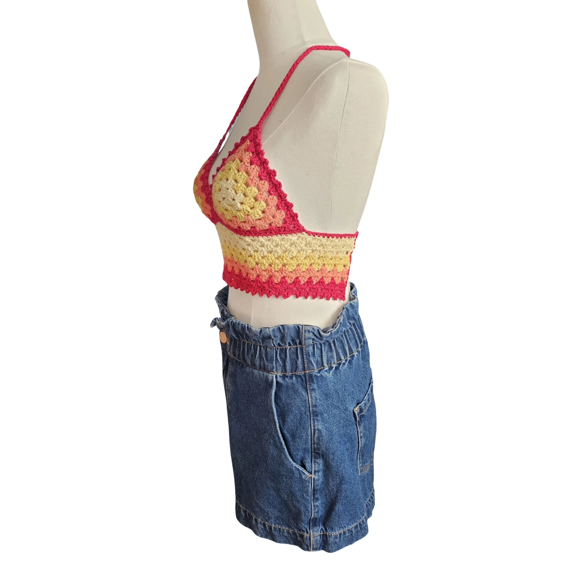 Mannequin wearing a colorful crochet top and blue denim shorts on a white background
