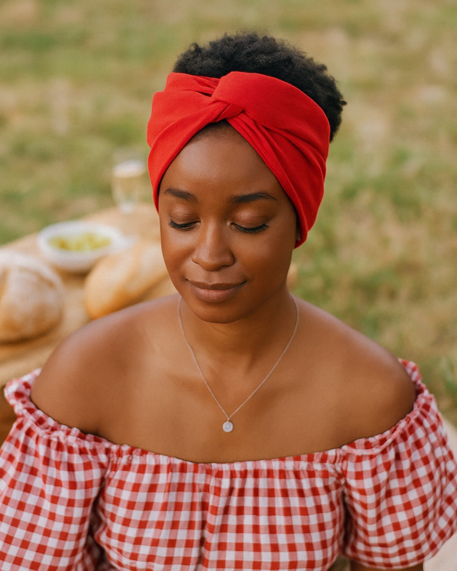 Woman wearing a red Wire headband and checkered top outdoors