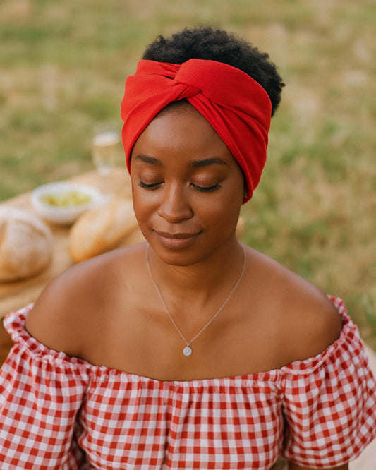 Woman wearing a red Wire headband and checkered top outdoors