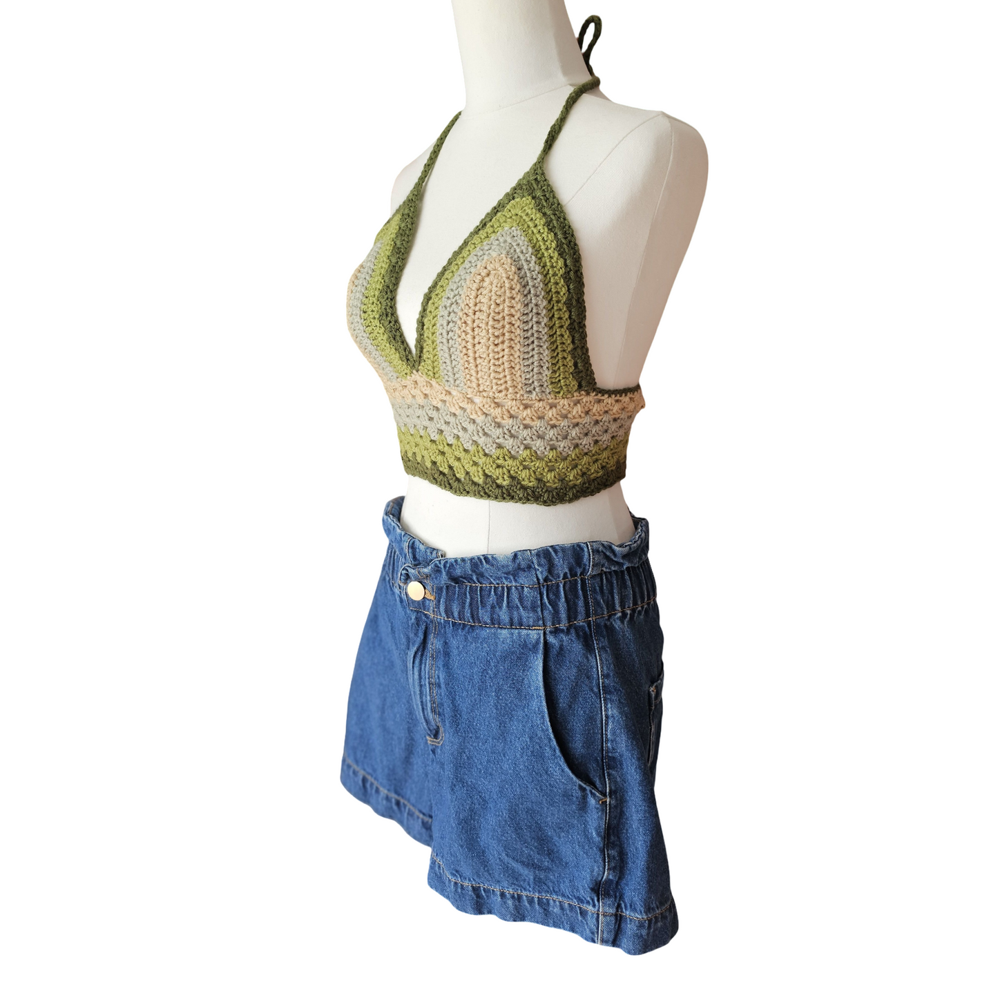 Mannequin wearing a green and beige crochet top with a blue denim skirt on a white background