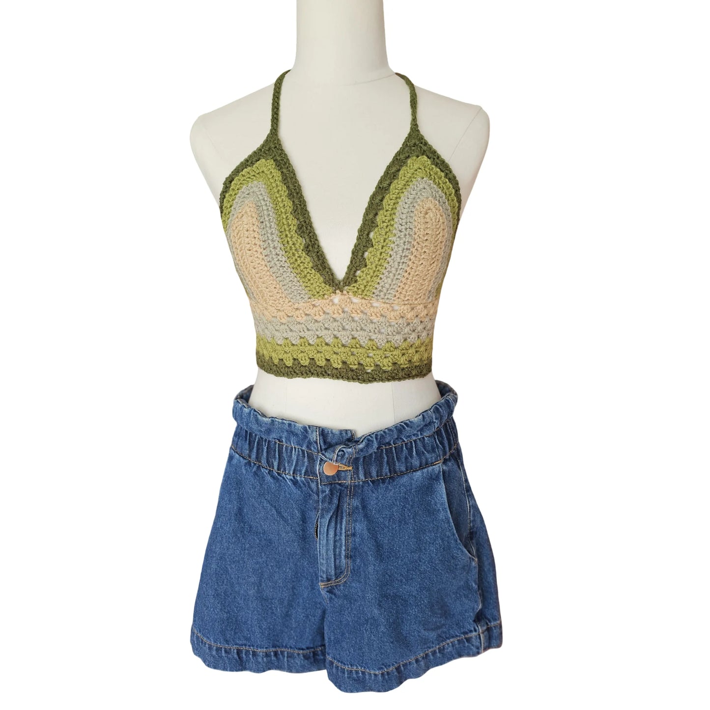 Mannequin wearing a green and beige crochet top with blue denim shorts on a white background