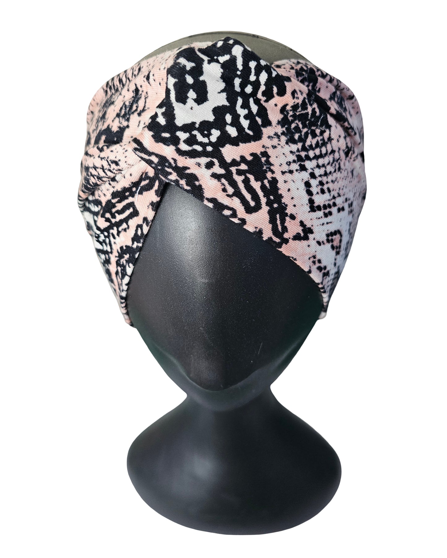 Turban with snake print on a black mannequin head against a white background