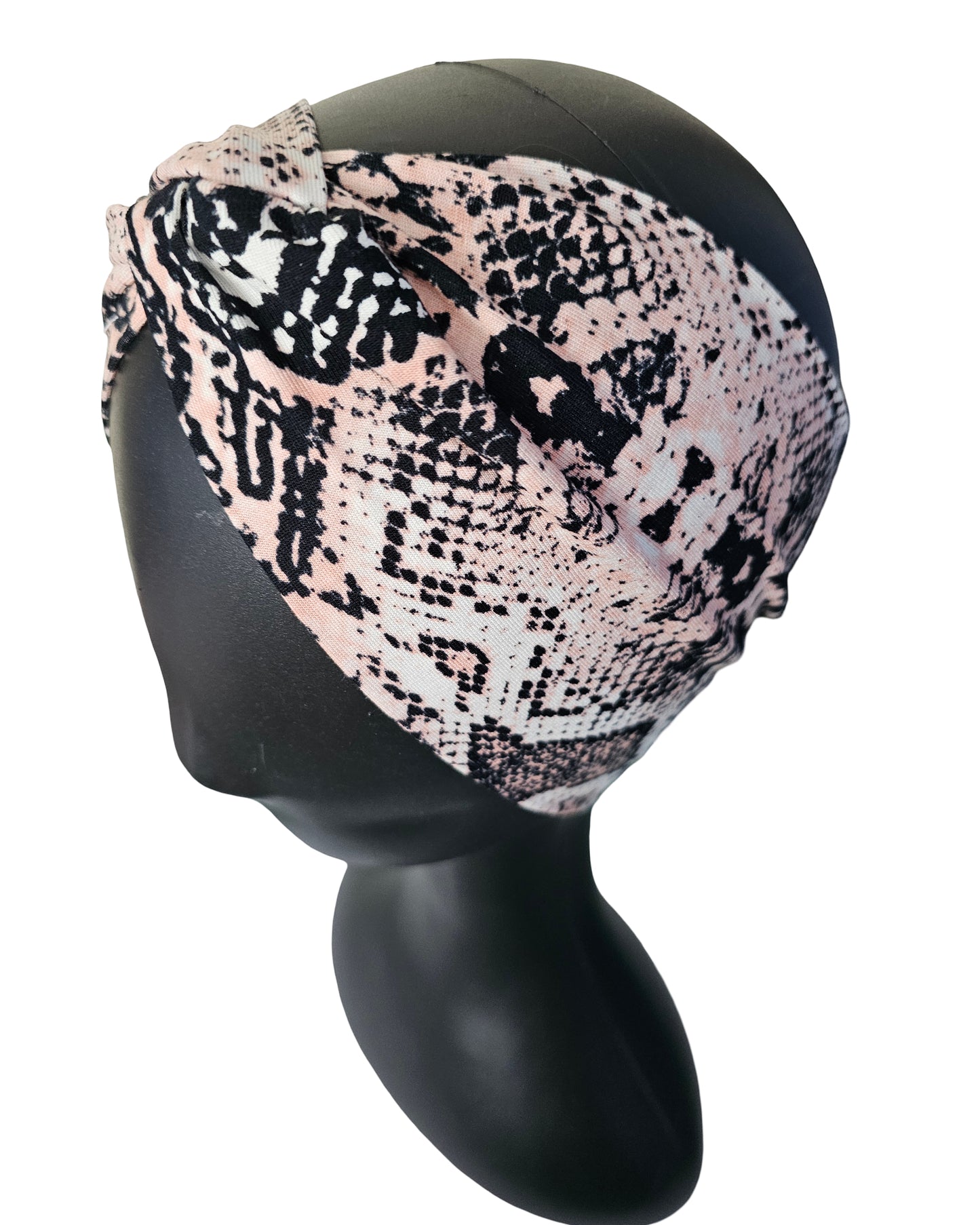Snakeskin patterned headscarf on a black mannequin head against a white background