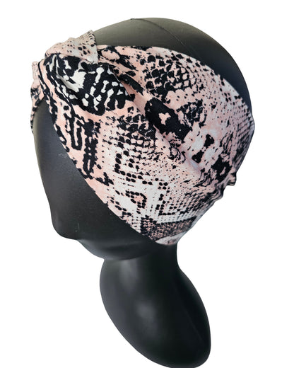 Snakeskin patterned headscarf on a black mannequin head against a white background