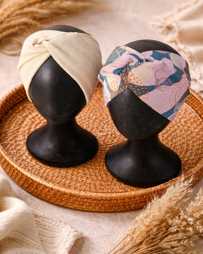 Two headbands on mannequin heads with a floral pattern and beige color, placed on a woven mat.