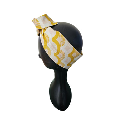 Yellow and white patterned wire headband on a mannequin head against a white background side view